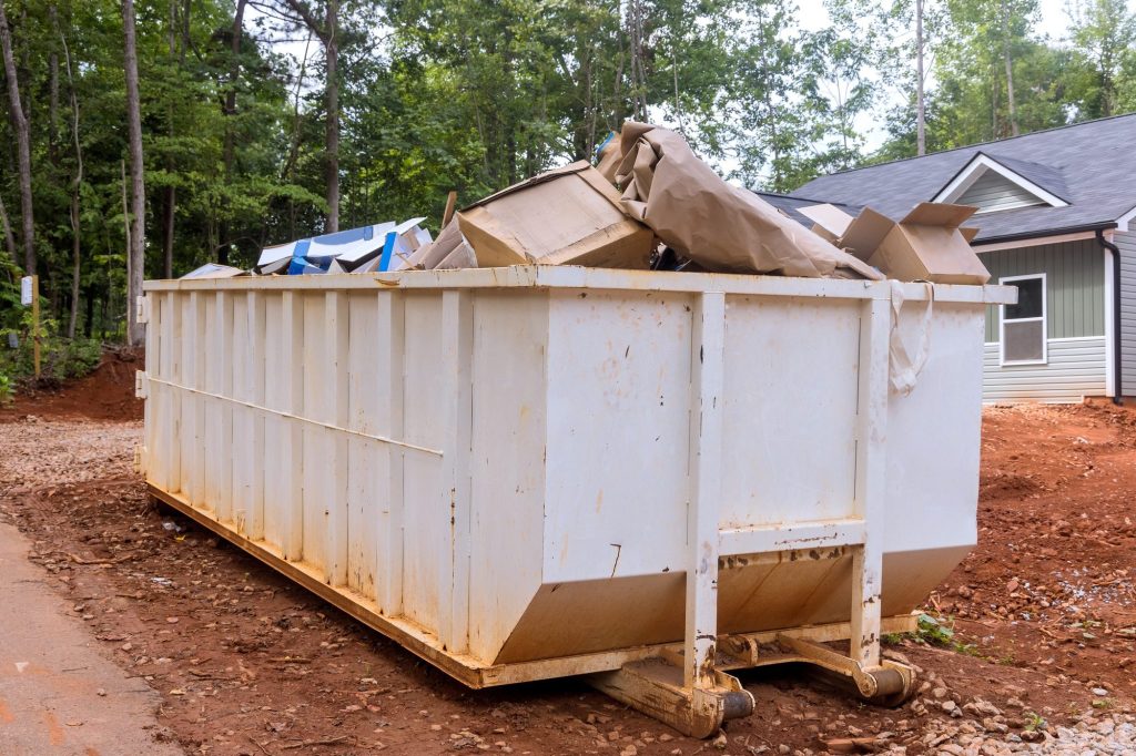 a rubbish removal container on of a house underneath an industrial building is used for waste -